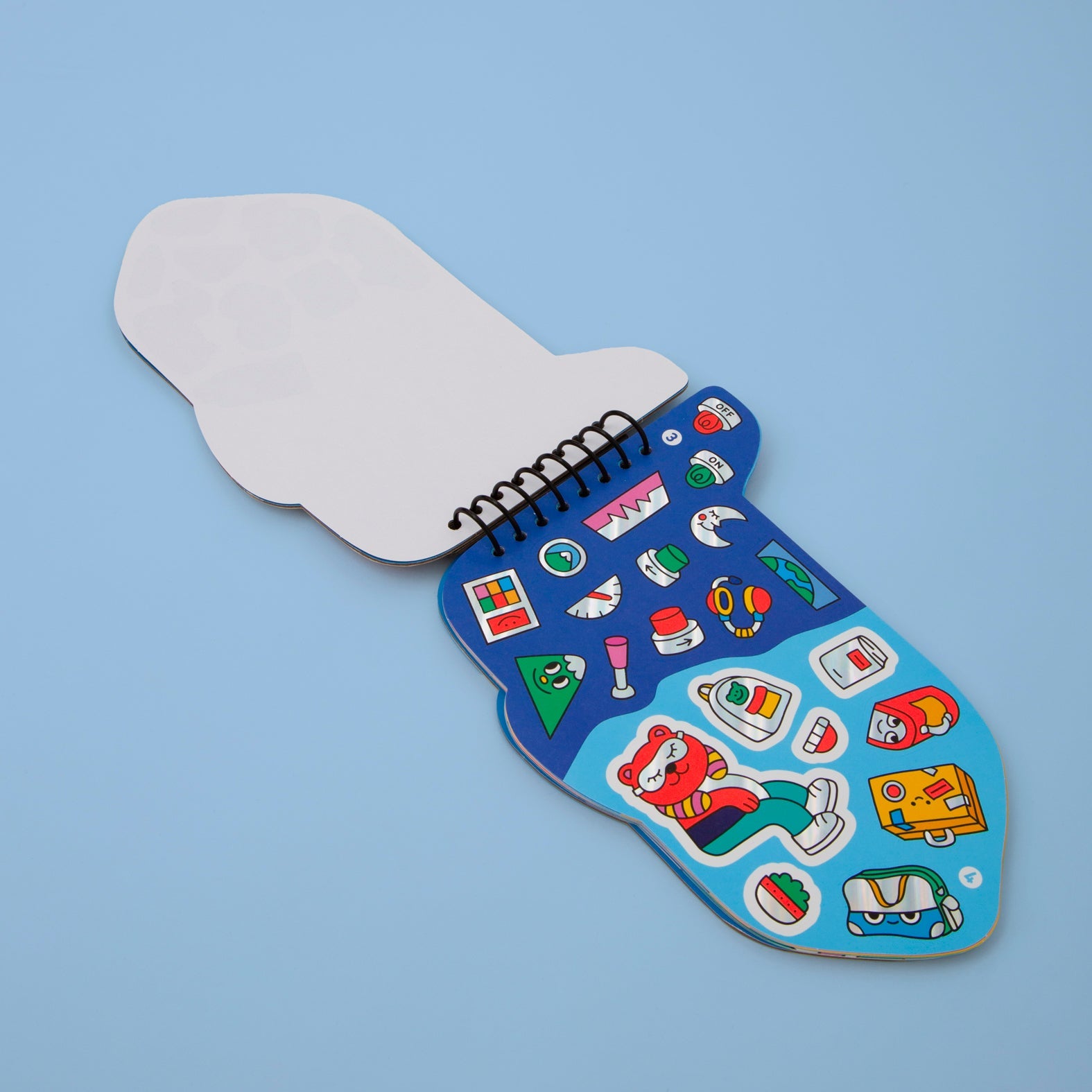 Carnet d'activités stickers Wroum OMY ouvert sur une planche de stickers de voyage : ours, valises, sacs et cartes, sur fond bleu ciel