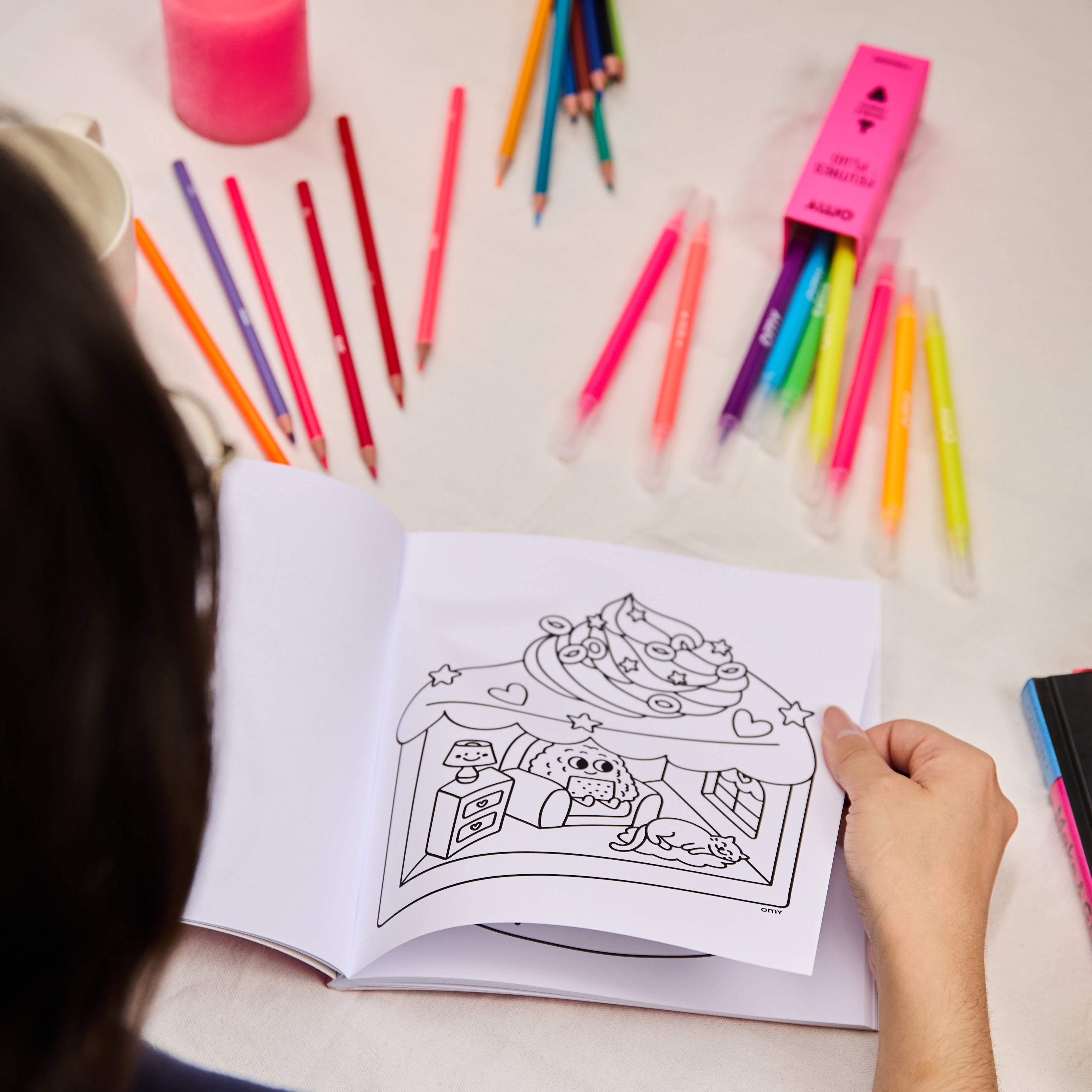 Cahier Cozy Art Kawaii ouvert avec page détachable illustrée en noir et blanc, prêt à être colorié, sur une table décorée de crayons et d’accessoires créatifs.