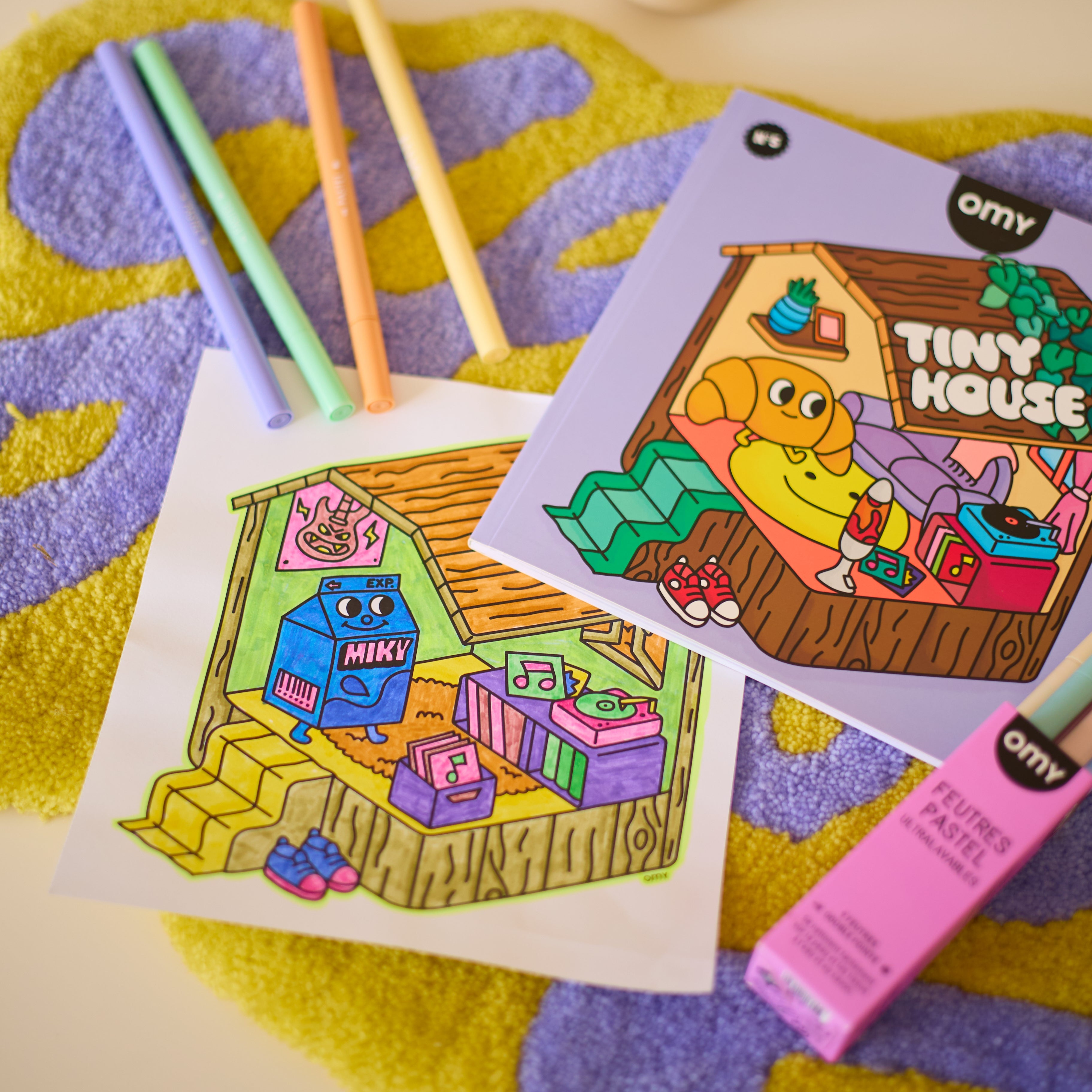 Illustration coloriée du cahier Tiny House OMY avec feutres pastel, page détachable d’un carnet de coloriage relaxant.