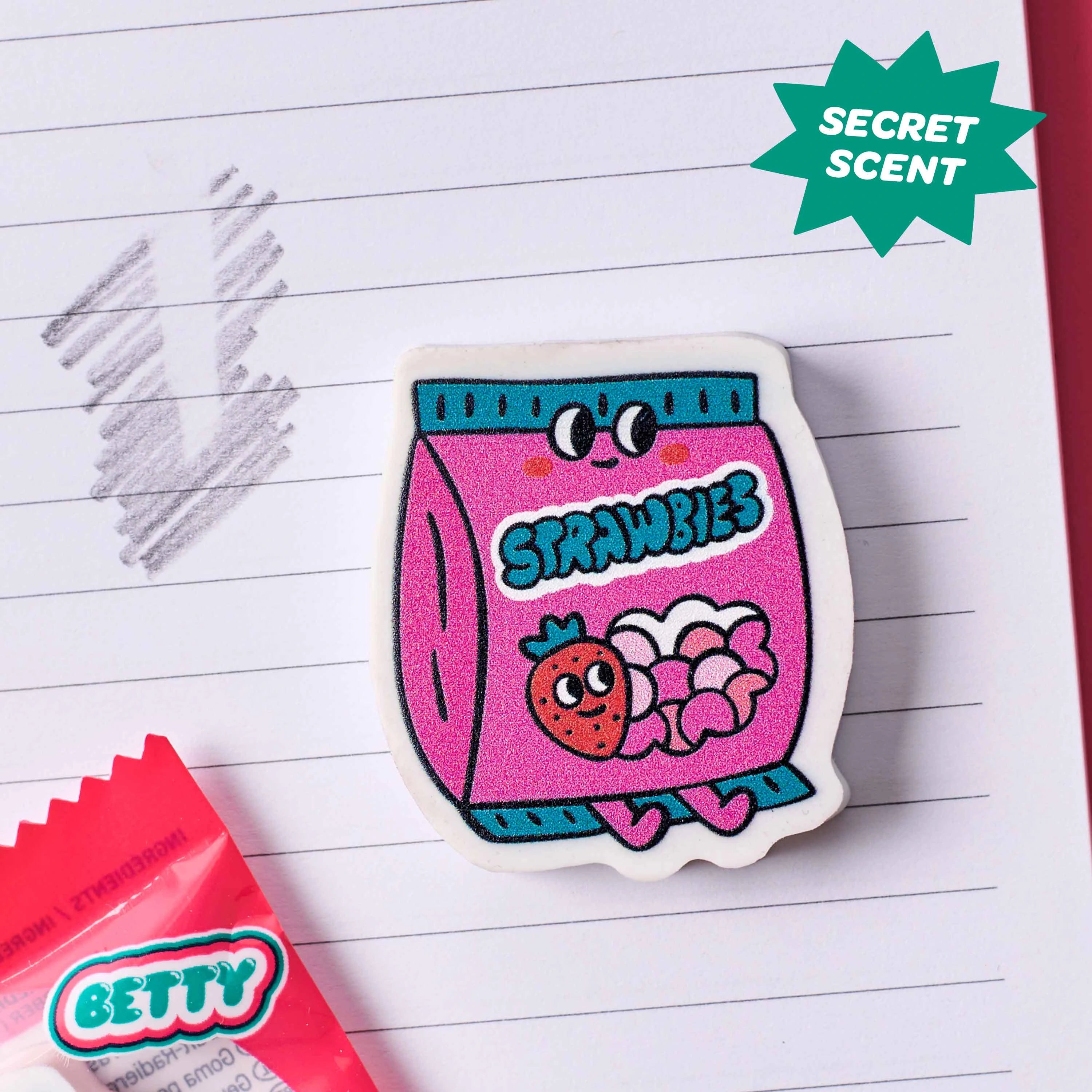 Gomme Betty OMY en forme de fraise utilisée sur carnet pour effacer crayon