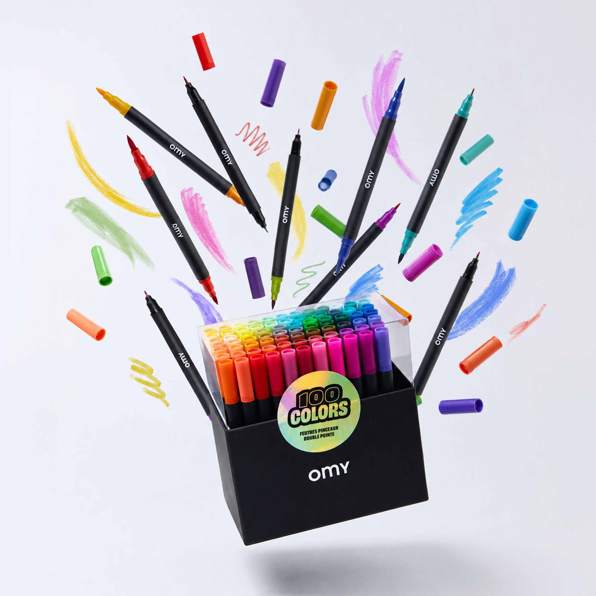 Mise en scène créative de la boîte de 100 feutres double-pointe OMY entourée de feutres et de tracés multicolores.