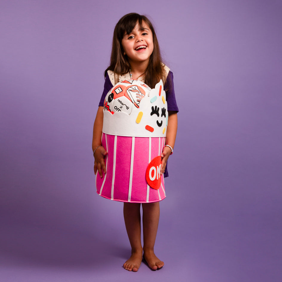 Enfant portant le Tidy bag - Yummy, panier de rangement cupcake en feutrine rose et blanc, amusant et décoratif pour chambre d’enfant.
