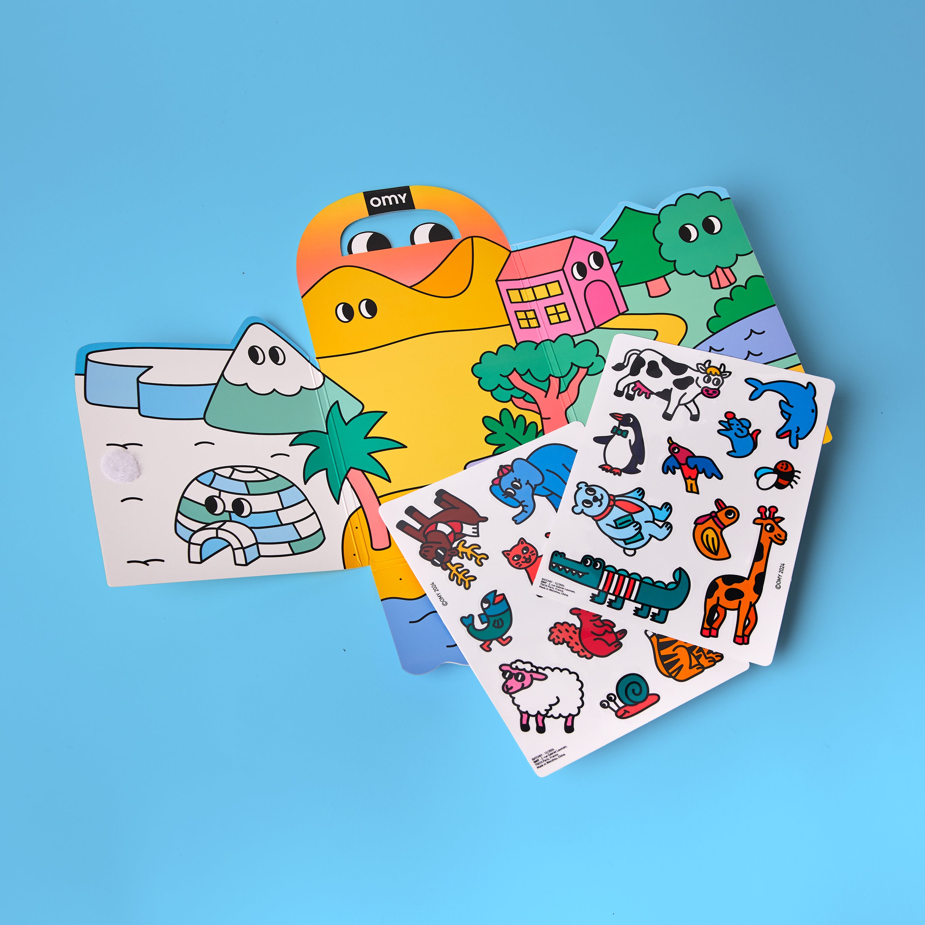Kit Montessori Stickers Animals OMY ouvert avec décor triptyque coloré et deux planches de stickers repositionnables représentant des animaux du monde entier.