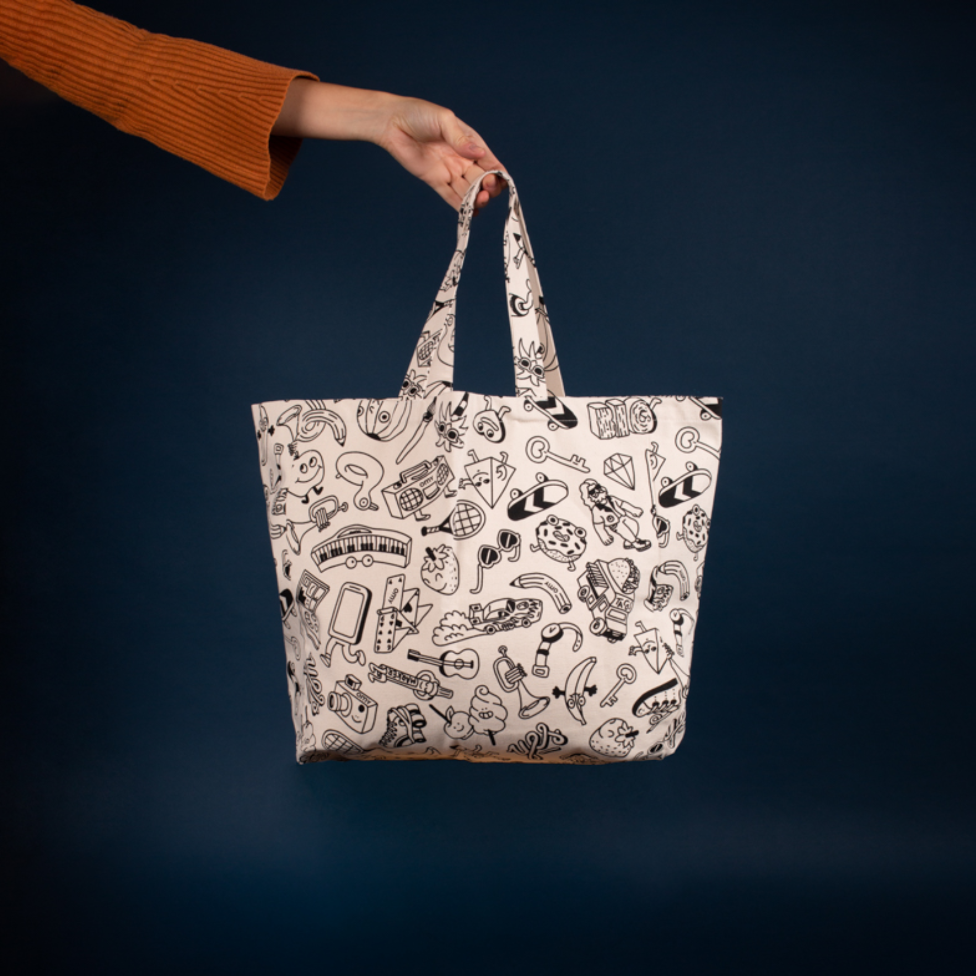 Hand hält die OMY Shopper-Tasche zum Ausmalen, Rohleinen mit schwarz-weißen Motiven, auf nachtblauem Hintergrund
