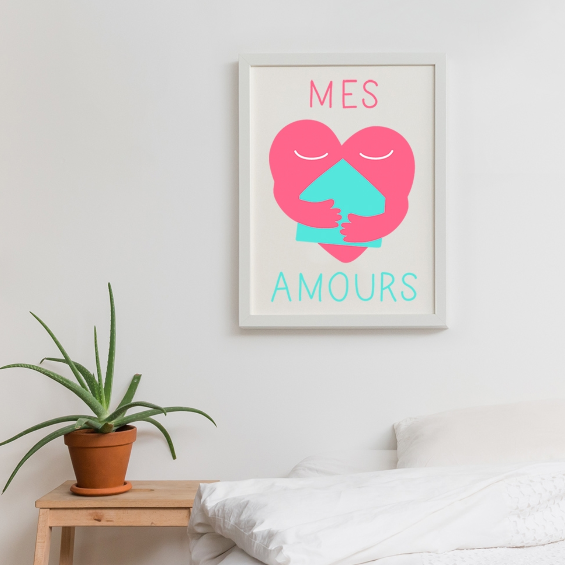 OMY Poster „Mes Amours“ gerahmt in einem Schlafzimmer: rosa Herz, das ein türkisfarbenes Haus umarmt, über einem weißen Bett