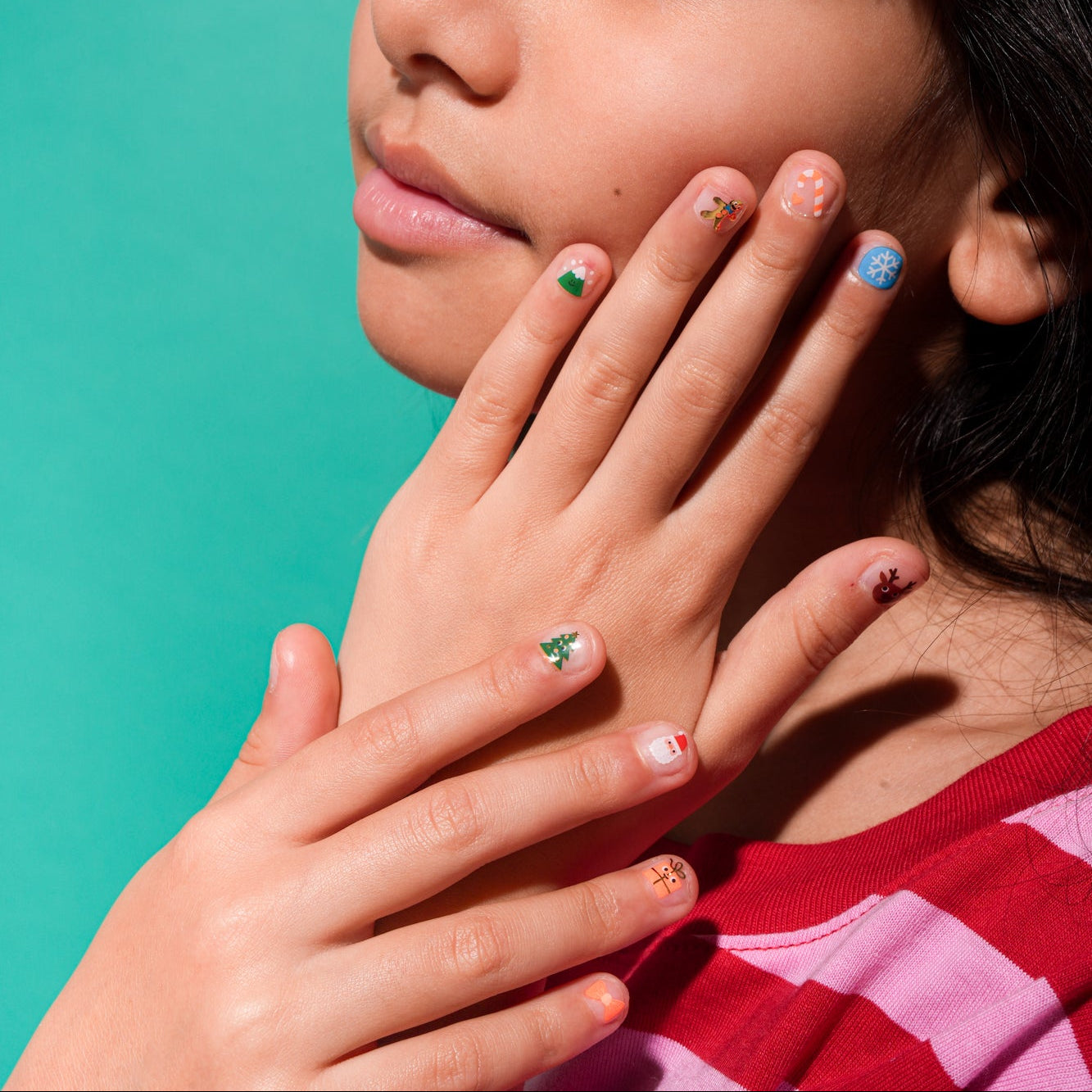 Gros plan sur les mains d’une enfant portant les autocollants d’ongles OMY "HO HO HO!" aux couleurs de Noël, faciles à poser et adaptés aux enfants.