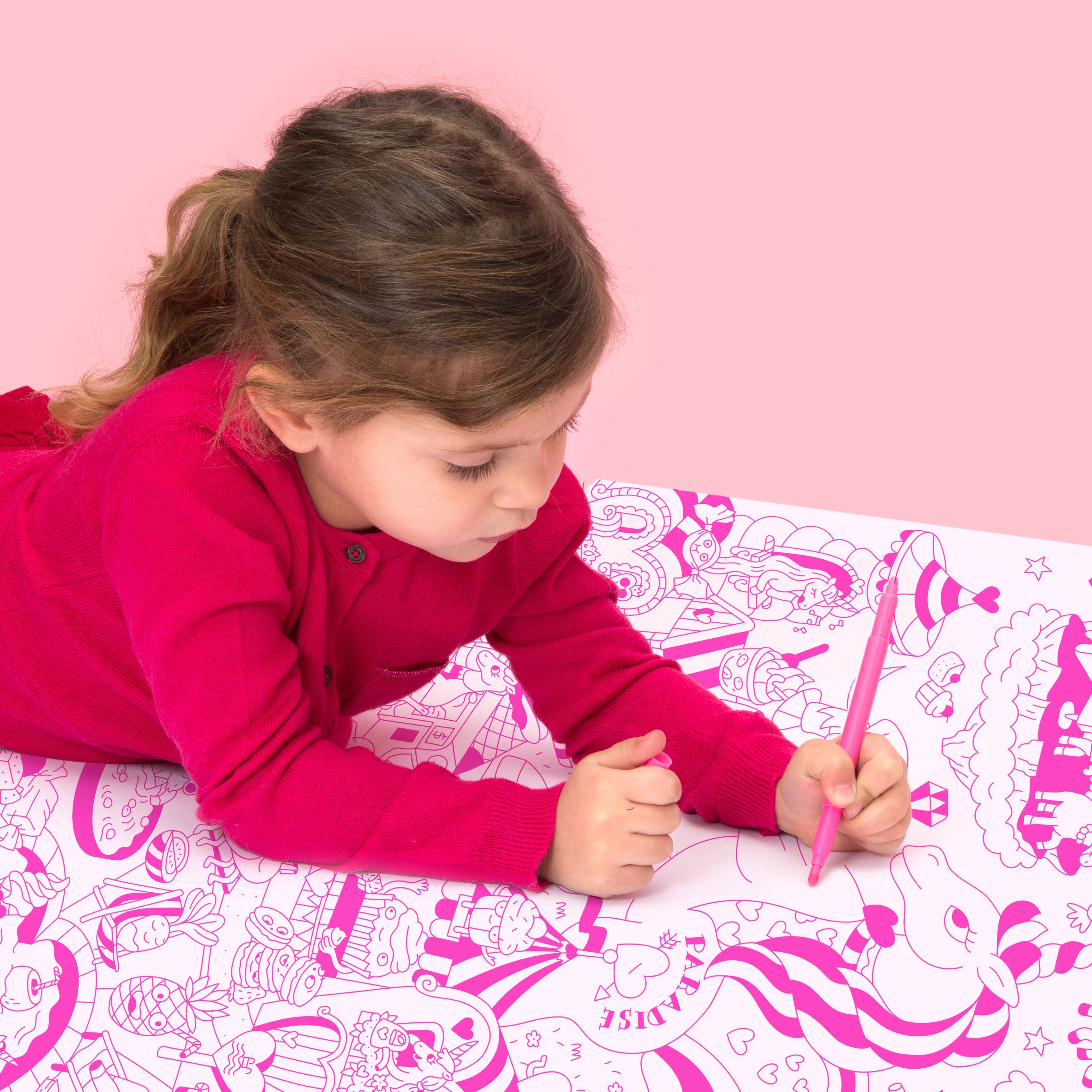 Fille concentrée en train de colorier le poster géant Lily LA LICORNE, tons rose fluo