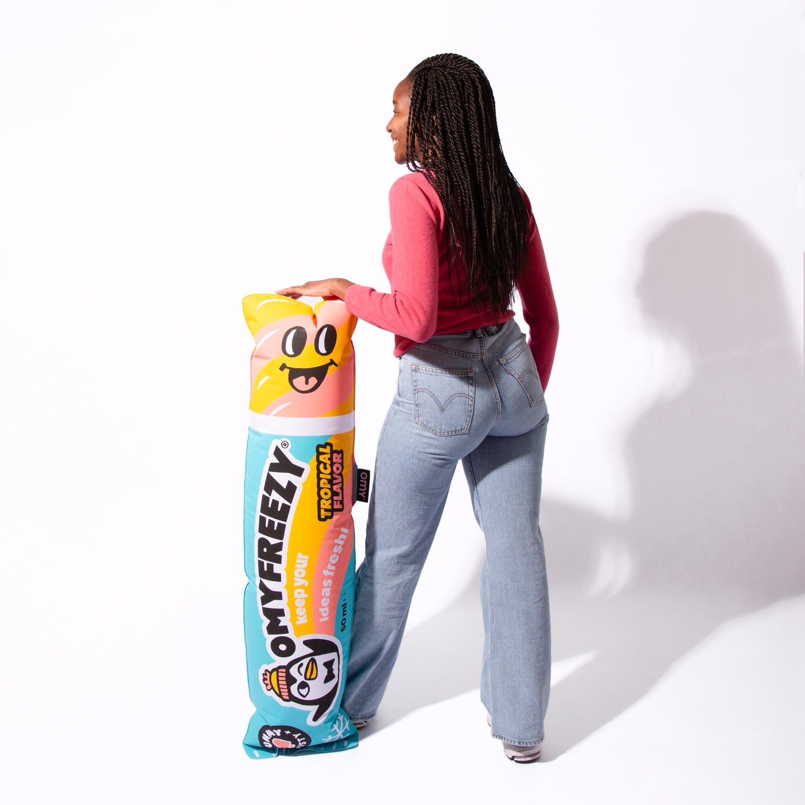 Jeune femme debout, main posée sur le pouf gonflable OMY Freezy en forme de glace à l'eau, qui lui arrive à la taille
