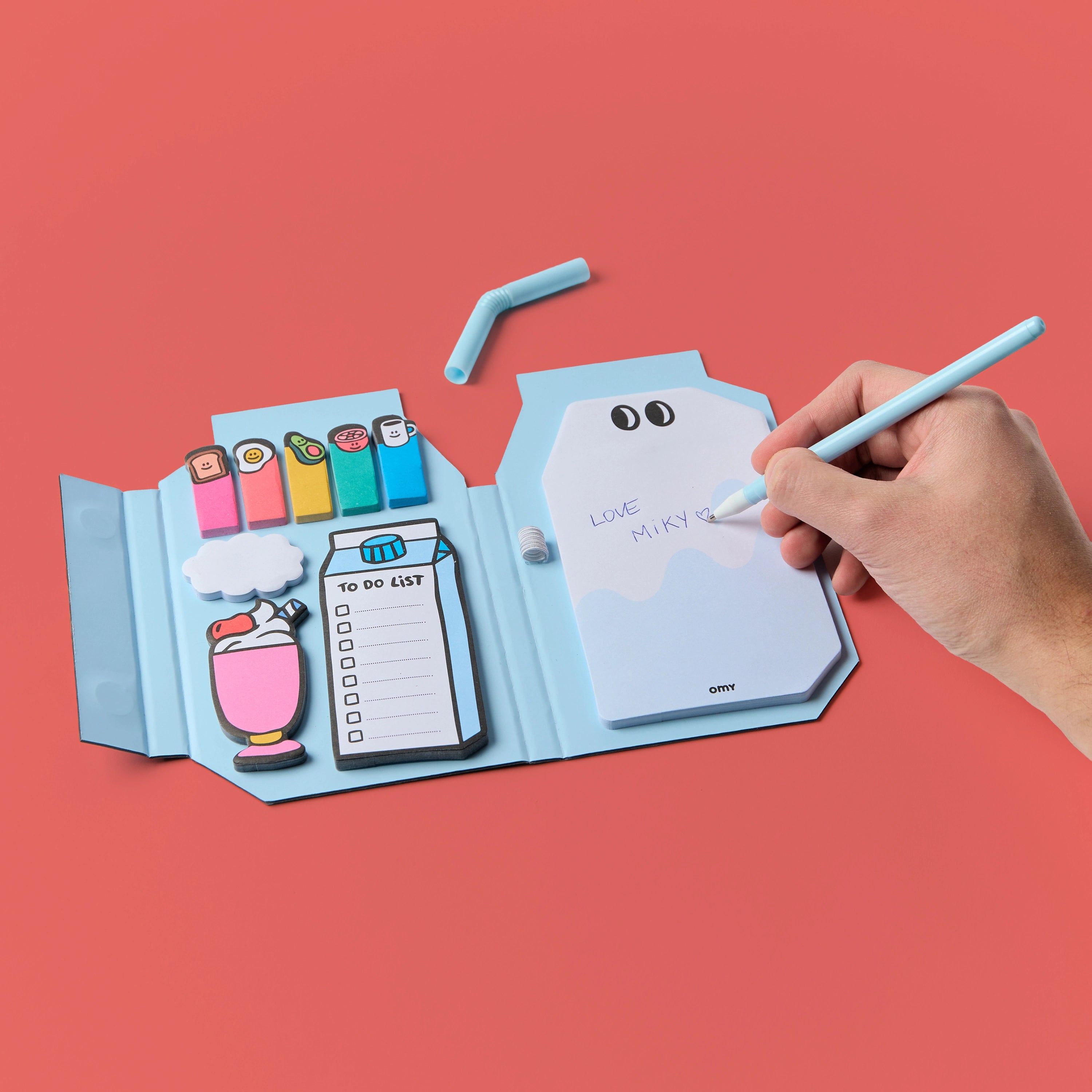 Sticky Notes Miky OMY ouvert – Mémos repositionnables colorés, paille-stylo et to-do list, une main écrit sur la page