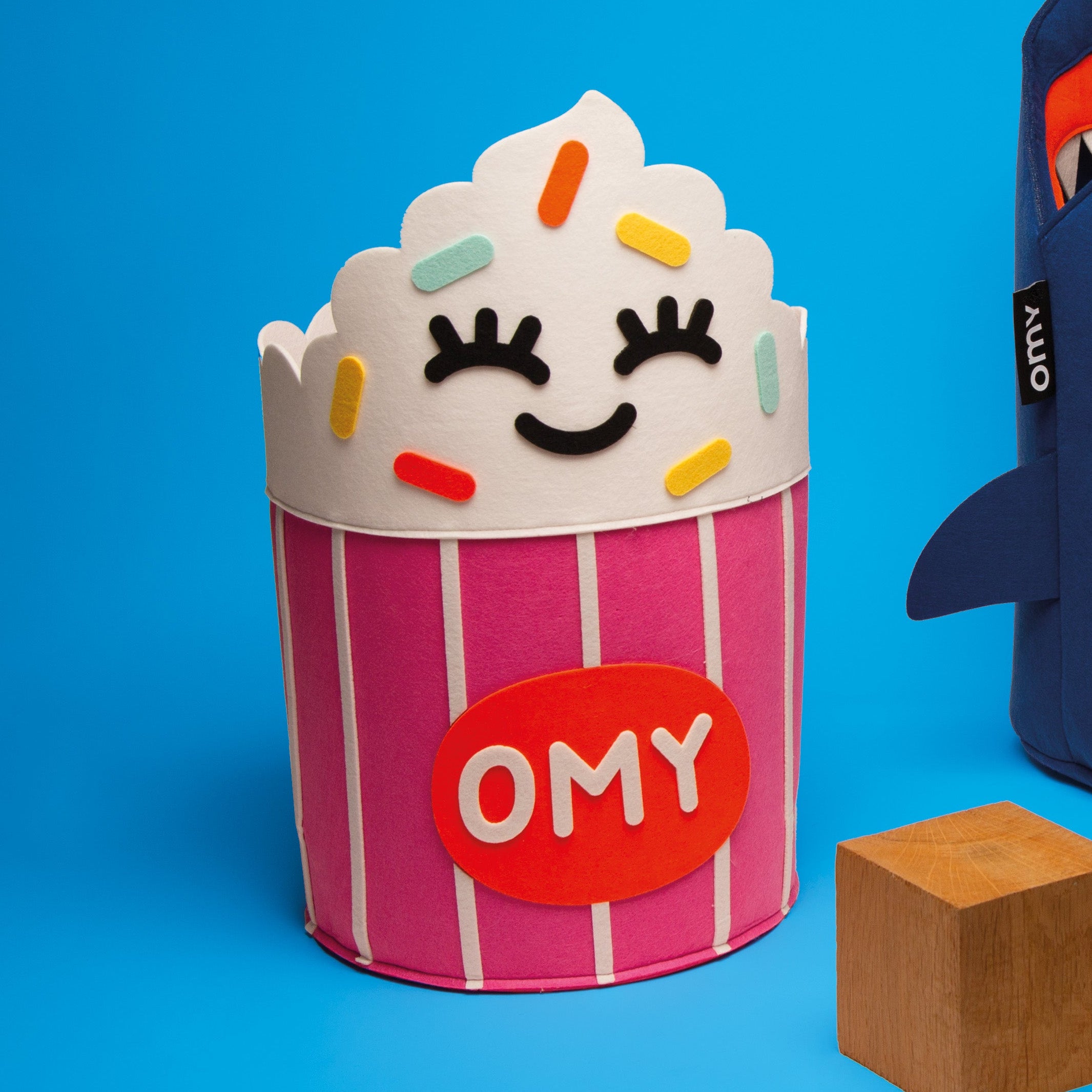 Tidy bag - Yummy, panier de rangement en feutrine en forme de cupcake rose rayé blanc avec décorations colorées et logo OMY.