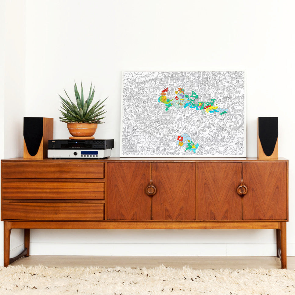 Affiche à colorier Switzerland encadrée et posée sur un meuble déco moderne suisse
