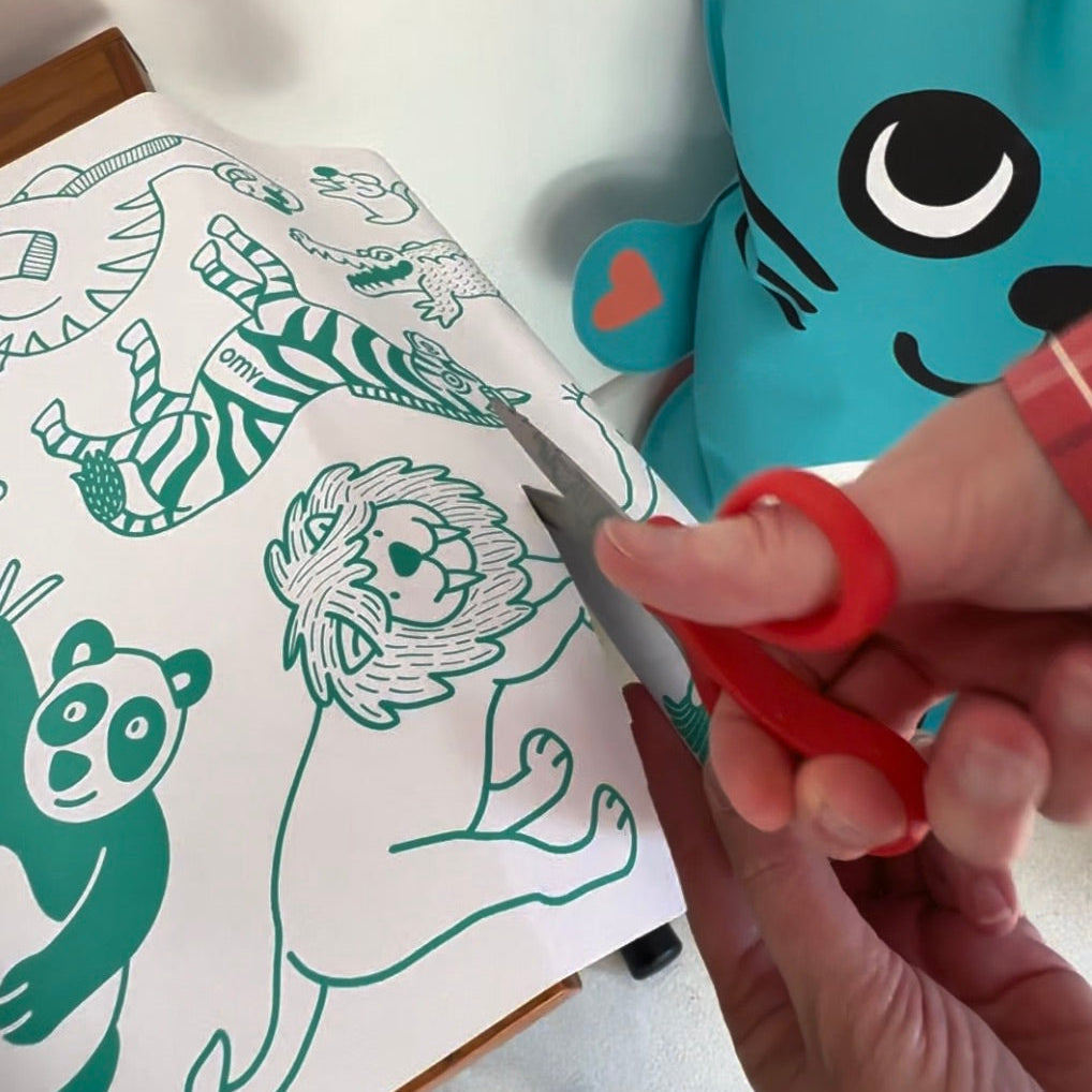 Main découpant papier sur le rouleau Stick-it ANIMALS, activité créative pour enfant
