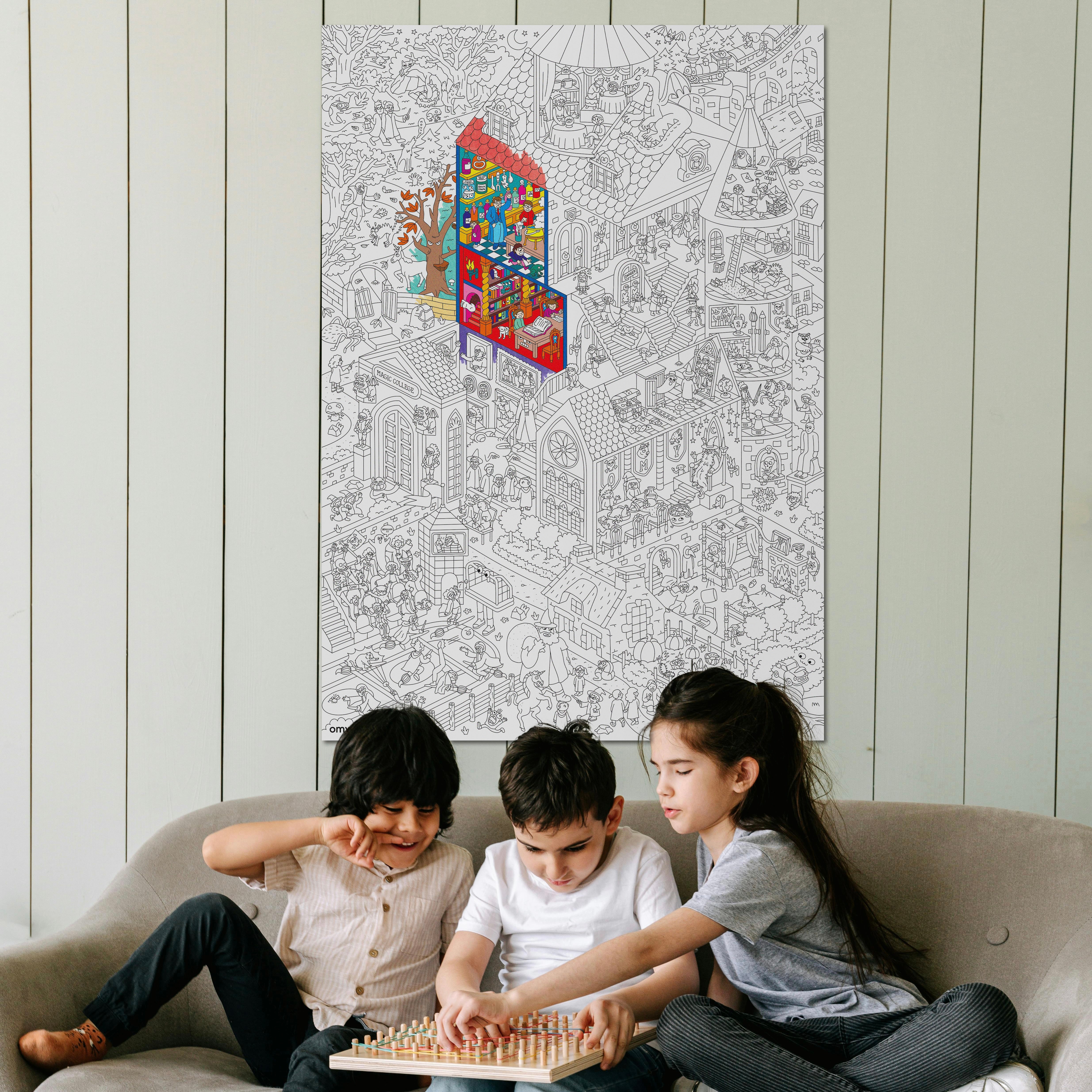 Trois enfants jouant devant le poster géant à colorier Magic College d’OMY affiché sur un mur – idéal pour décorer et animer une chambre avec créativité.