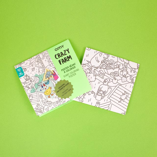 Flatlay der Verpackung Crazy Farm von OMY mit Ausmalposter-Motiv auf grünem Hintergrund.