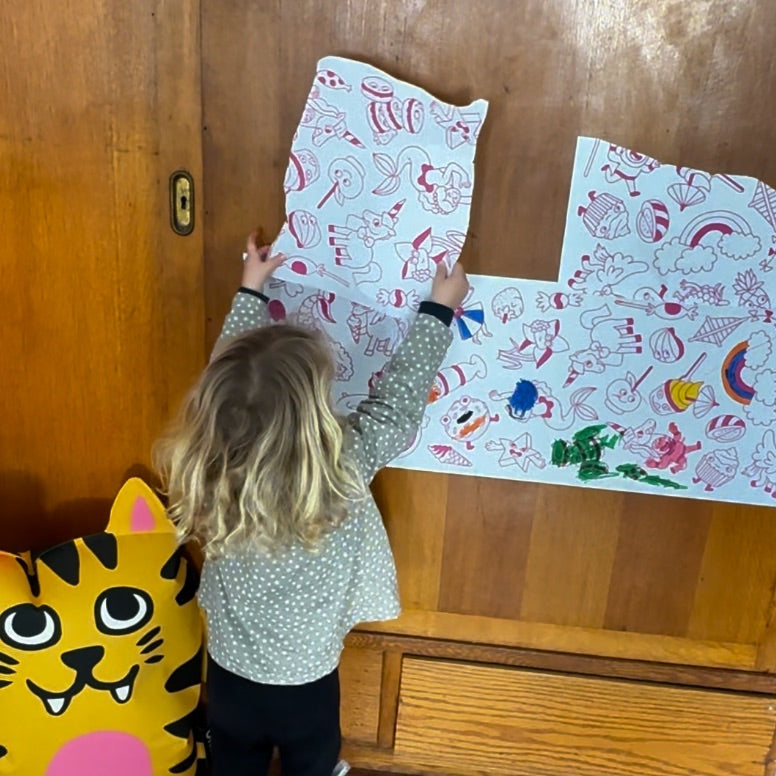 Petite fille appliquant des feuilles de papier adhésif Dreamland sur un mur en bois, activité manuelle idéale pour développer la créativité.