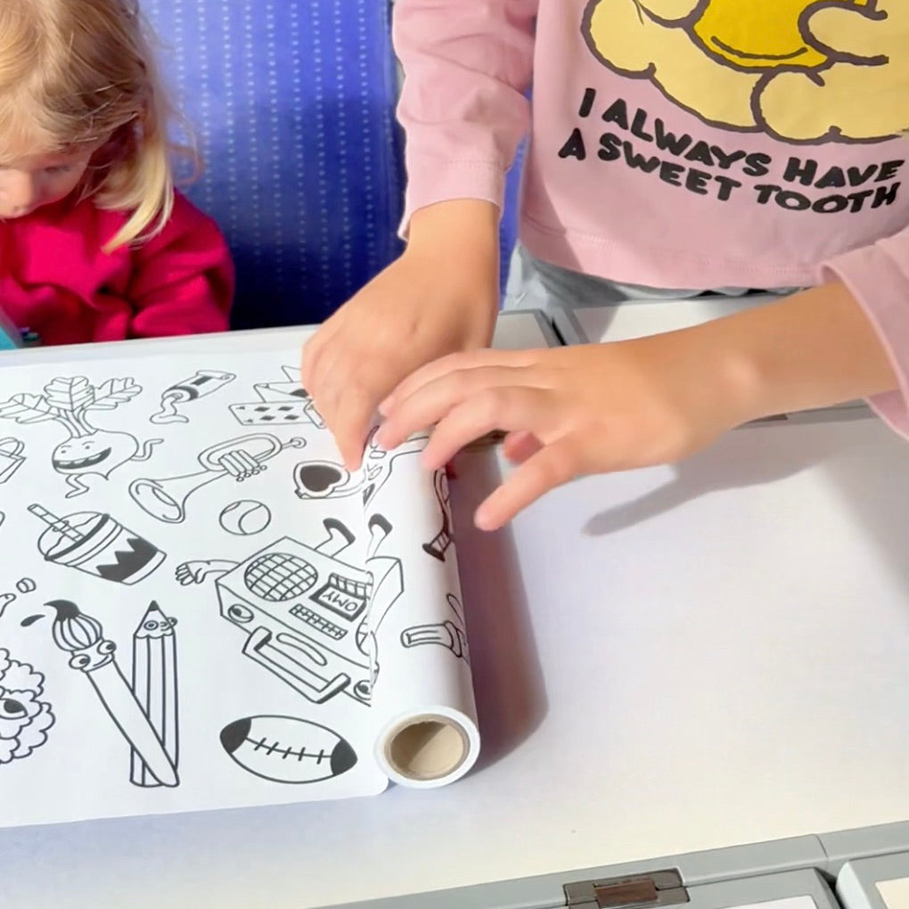 Enfants déroulant le rouleau Stick-it POP sur une table, prêt pour une activité de coloriage.