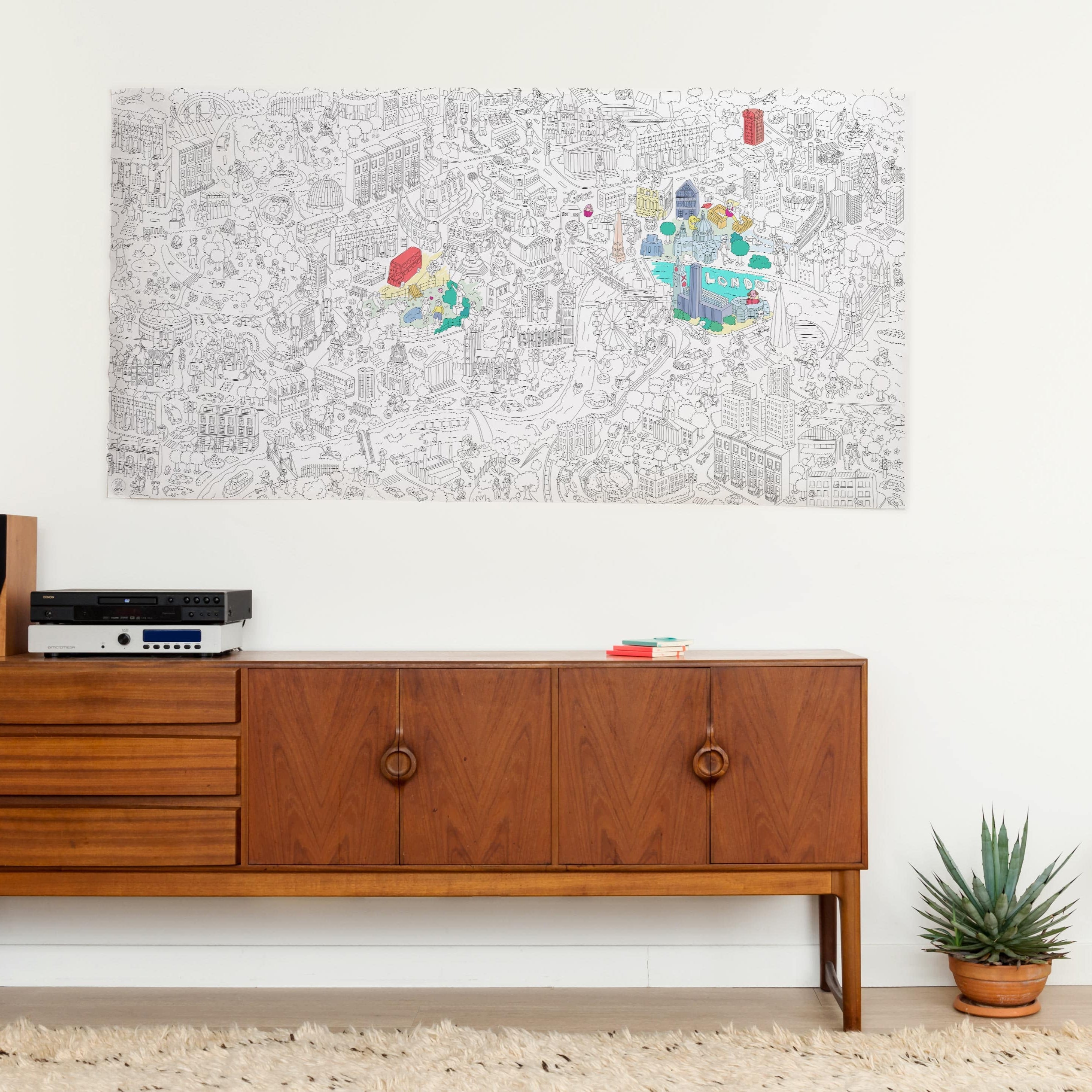 Póster gigante para colorear OMY London colgado en la pared sobre un aparador de madera vintage, parcialmente coloreado en colores vivos.