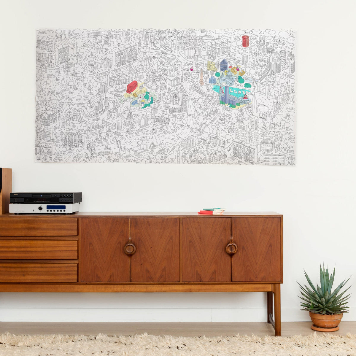 Poster gigante da colorare OMY London appeso al muro sopra una credenza in legno vintage, parzialmente colorato con colori vivaci.