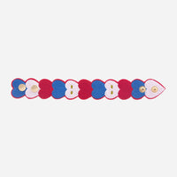 Bracelet brodé OMY à cœurs bleus, blancs et rouges posé à plat, avec ses boutons pression dorés, sur fond blanc
