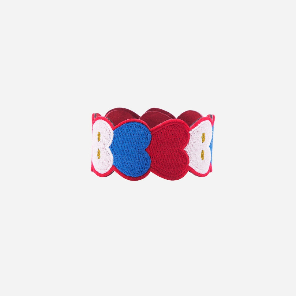 Bracelet brodé OMY à cœurs bleus, blancs et rouges, sur fond blanc