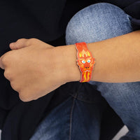 Bracelet OMY dragon rouge et orange porté au poignet d'un enfant, bras posé sur un genou en jean