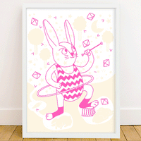Affiche OMY lapin rose au hula hoop dans un cadre blanc, posée au sol contre un mur blanc