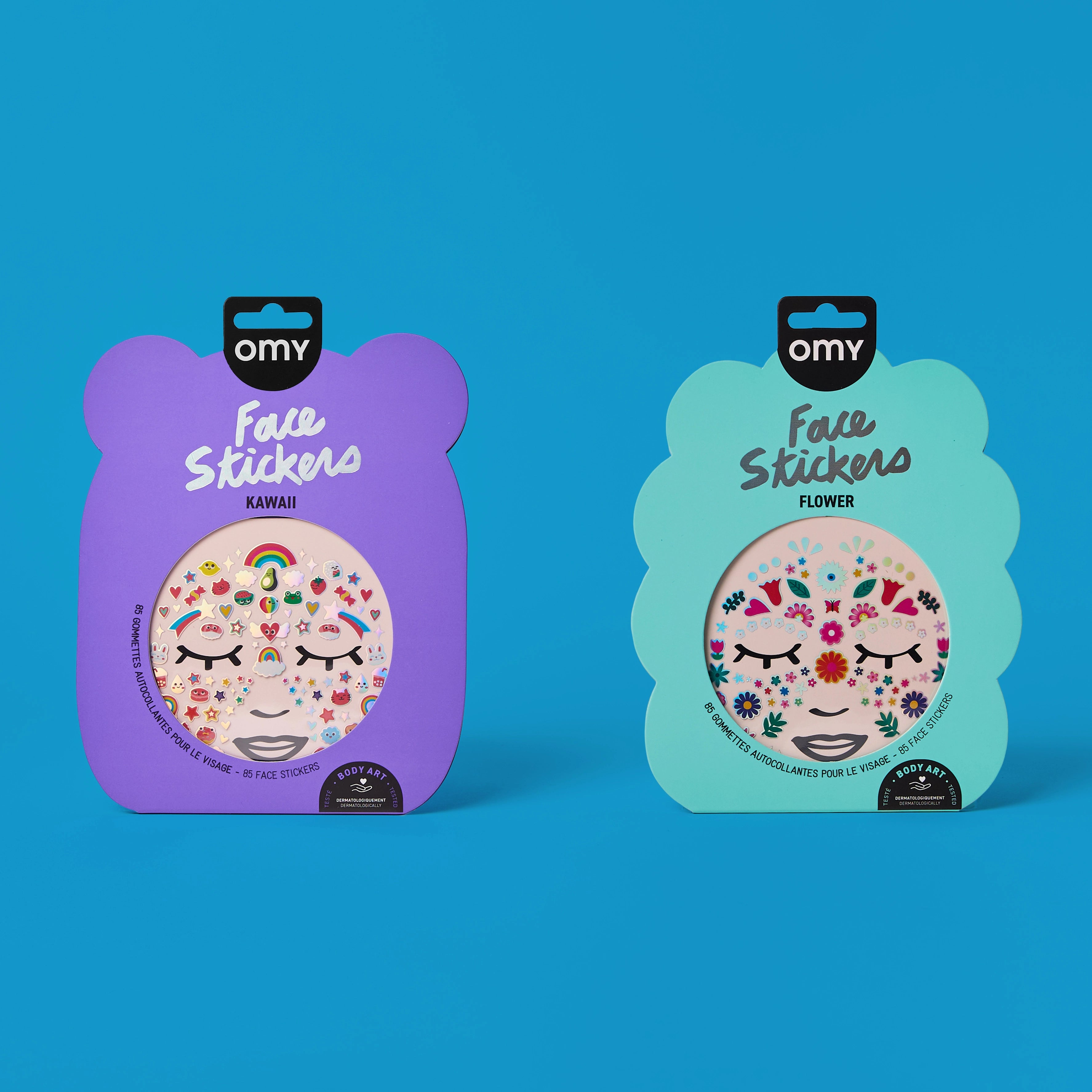 Duo de Face Stickers OMY Kawaii et Flower dans leurs emballages violet et vert d'eau, planches de stickers visage colorés sur fond bleu