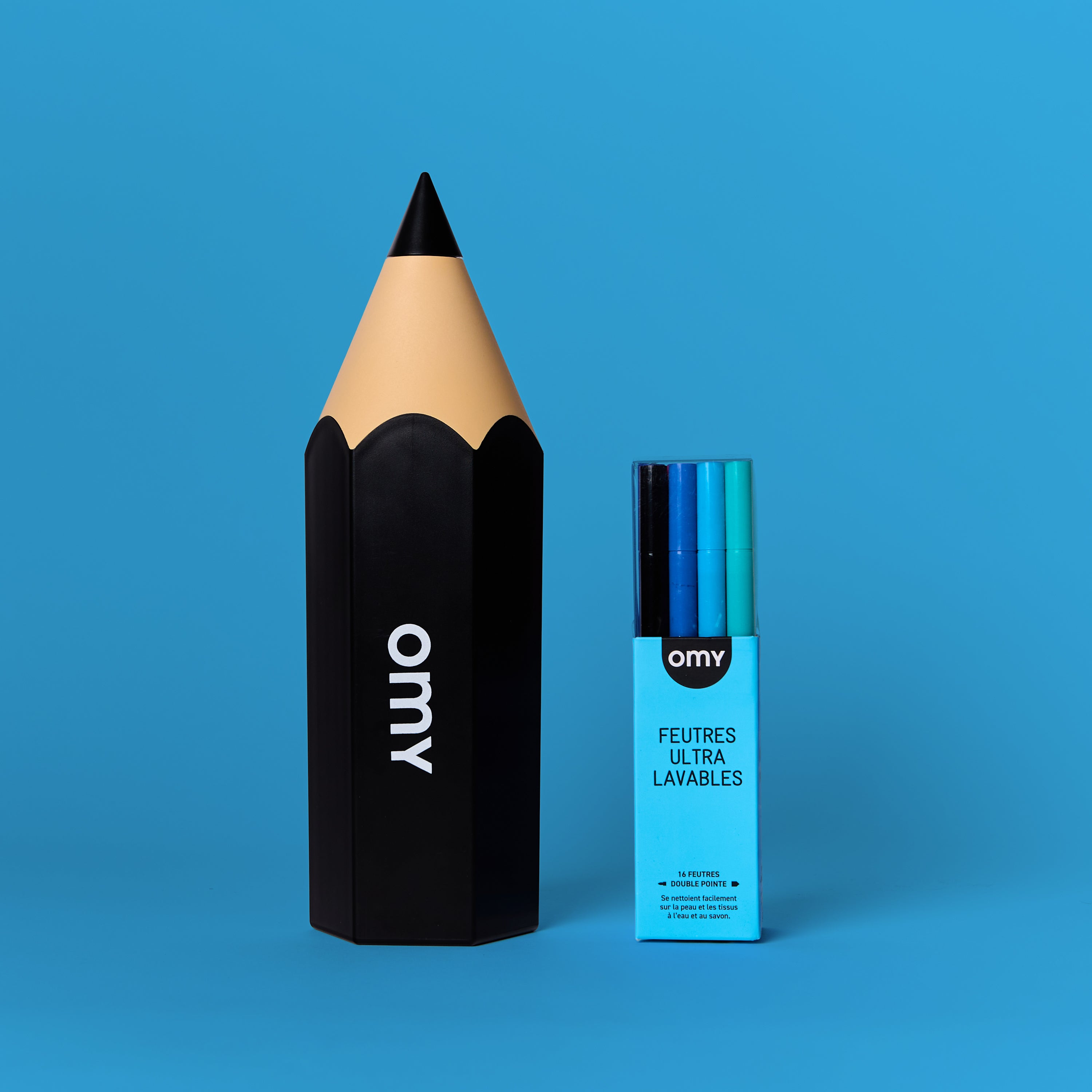 Closed black pencil case with OMY logo and ultra-washable markers in their matching blue case, on a plain blue background.