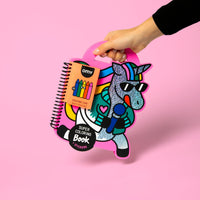 Mano sosteniendo el Super Coloring Book Lily OMY con forma de unicornio brillante con gafas de sol, cuaderno para colorear con stickers y 5 crayones de cera