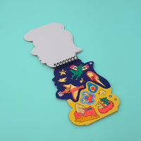 Dino OMY sticker activity book open to a page of dinosaur stickers, meteorite and fossils, on a turquoise background.