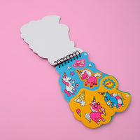 Carnet d'activités stickers Lily OMY ouvert sur une planche de stickers licornes, glaces, soleil et étoiles, sur fond rose