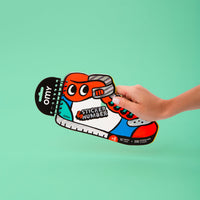 Hand holding the Sticker by Number Street OMY book shaped like a sneaker: 10 cards and 200 stickers, ages 6 and up.
