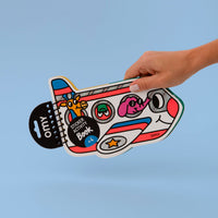 Main tenant le Sticker Activity Book Wroum OMY en forme d'avion holographique avec girafe et éléphant aux hublots, dès 4 ans