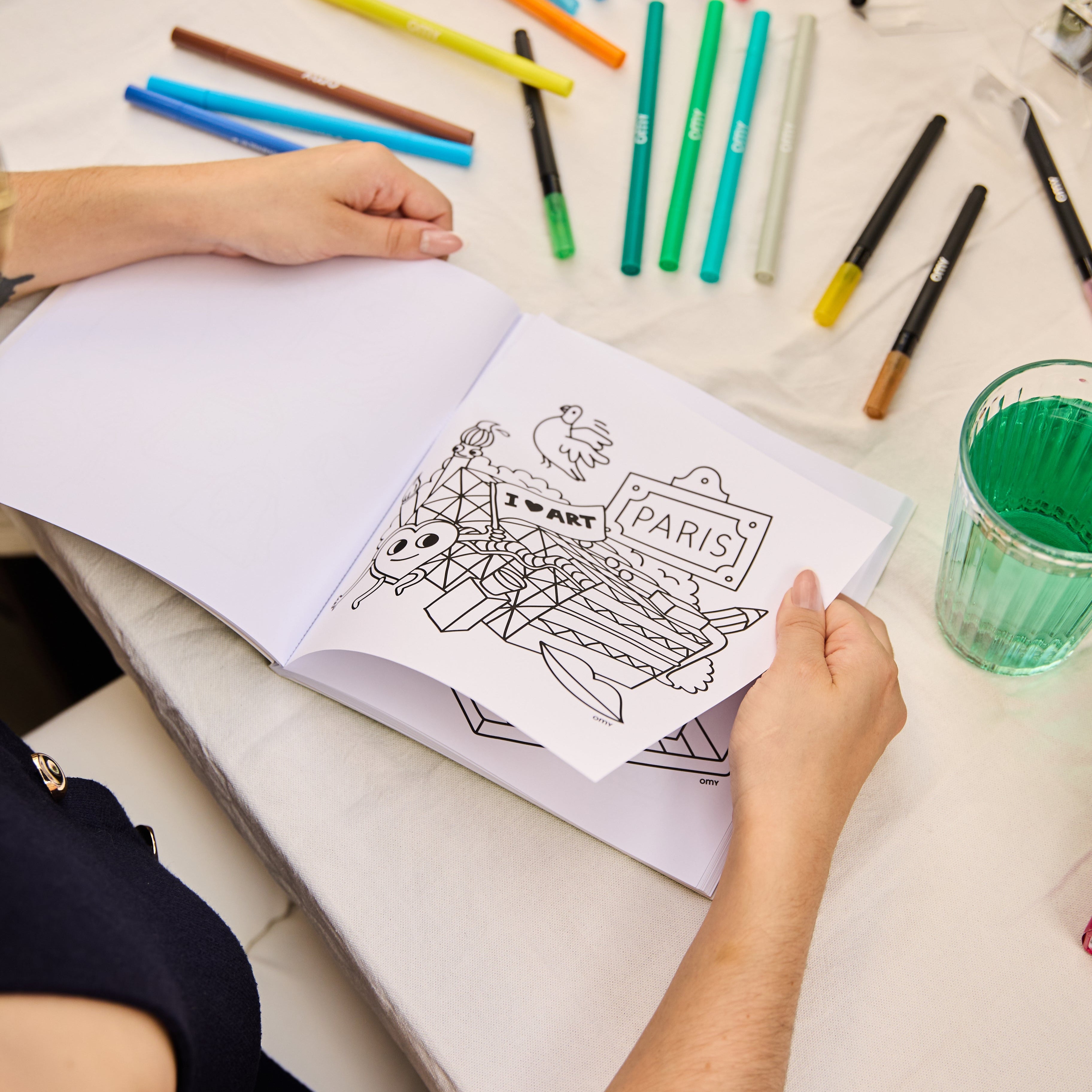 Kleurboek Cozy Art Paris opengeslagen op een uitscheurbare pagina met iconische elementen van Parijs, omringd door gekleurde stiften