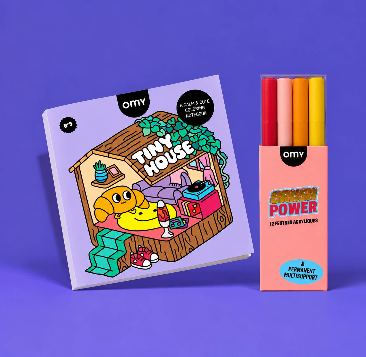 Carnet de coloriage OMY Tiny House Cozy Art avec une cabane illustrée, et étui de 4 feutres acryliques Brush Power rouge, rose, orange et jaune, sur fond violet