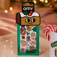 Pack Fabulous Stickers Noël OMY présenté dans une ambiance festive avec guirlandes lumineuses et sucres d’orge.