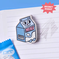 Miky OMY eraser shaped like a milk carton, being used on a notebook to erase