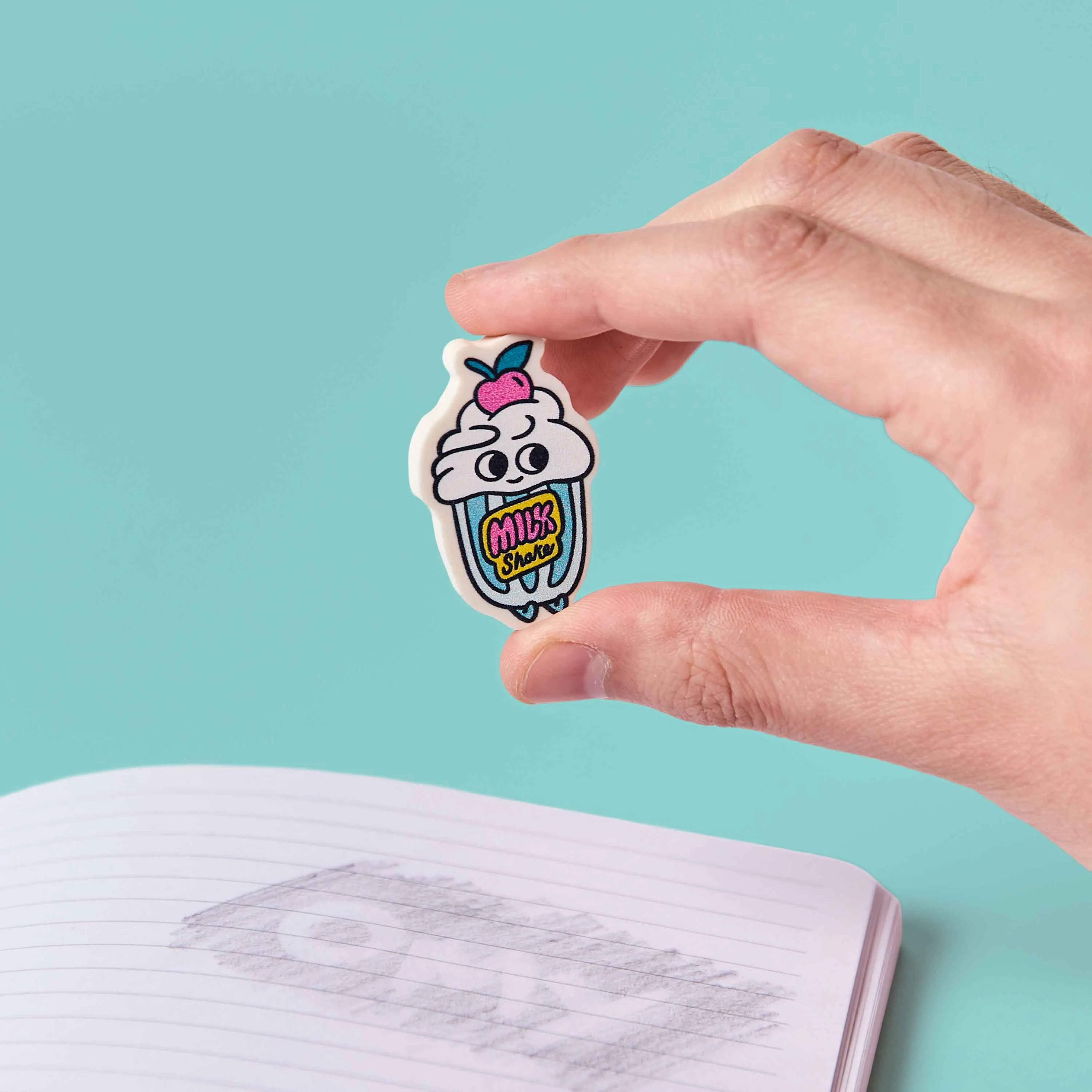 gomme milkshake kawaii Shaky OMY tenue en main au dessus carnet ecole
