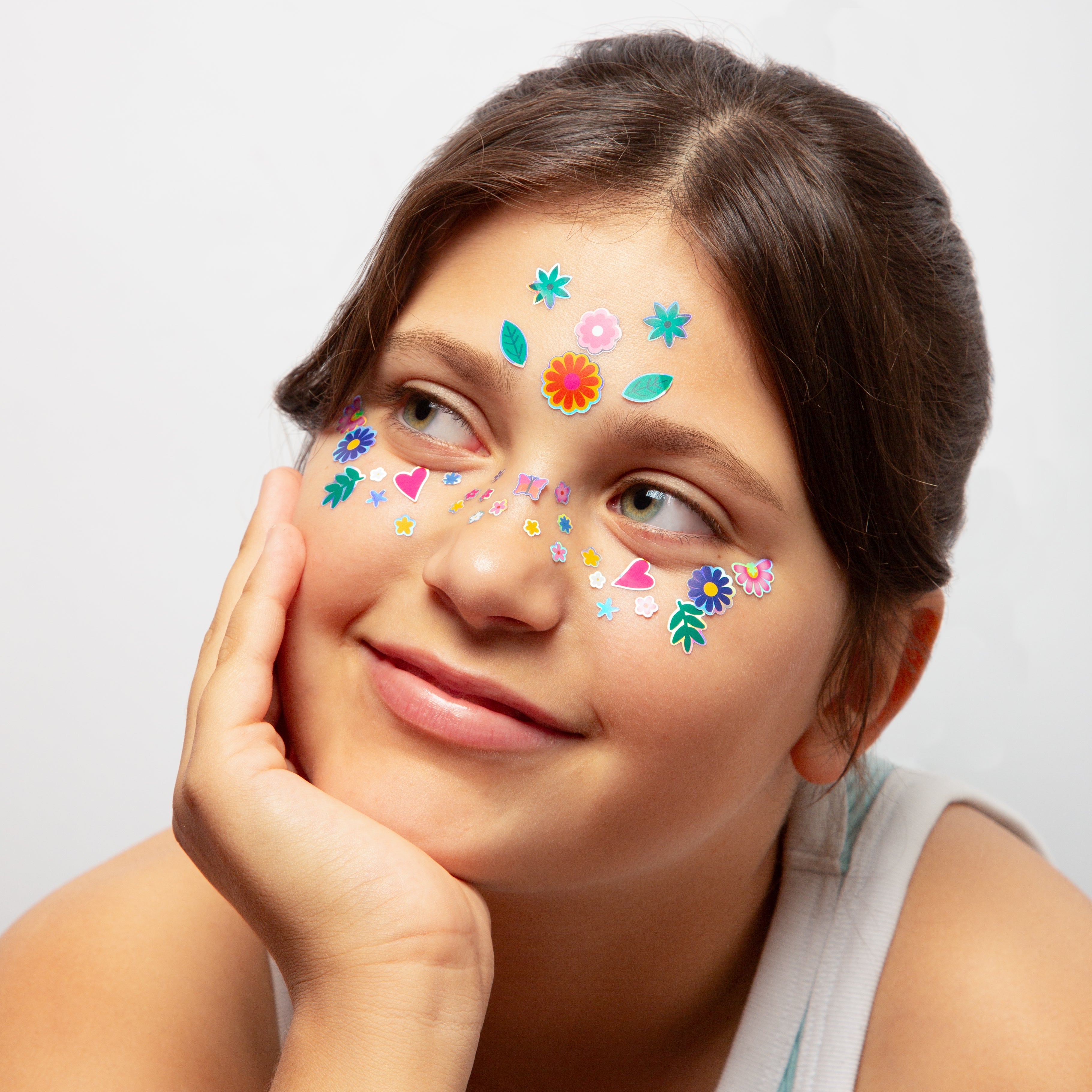 Enfant souriante portant les Face Stickers Flower OMY : fleurs, feuilles et cœurs colorés sur le front et les joues