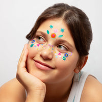 Enfant souriante portant les Face Stickers Flower OMY : fleurs, feuilles et cœurs colorés sur le front et les joues