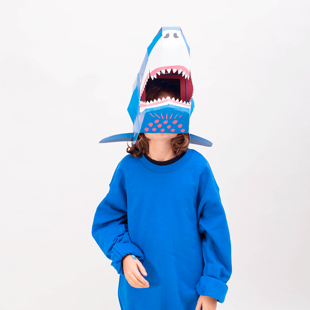 Enfant portant le masque 3D requin Sharky OMY en carton bleu, visage visible dans la gueule, sur fond blanc