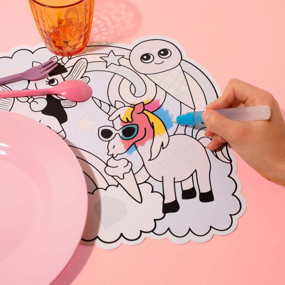 Main coloriant à l'eau la licorne du set de table Magic Water Lily OMY, avec assiette, verre et couverts roses
