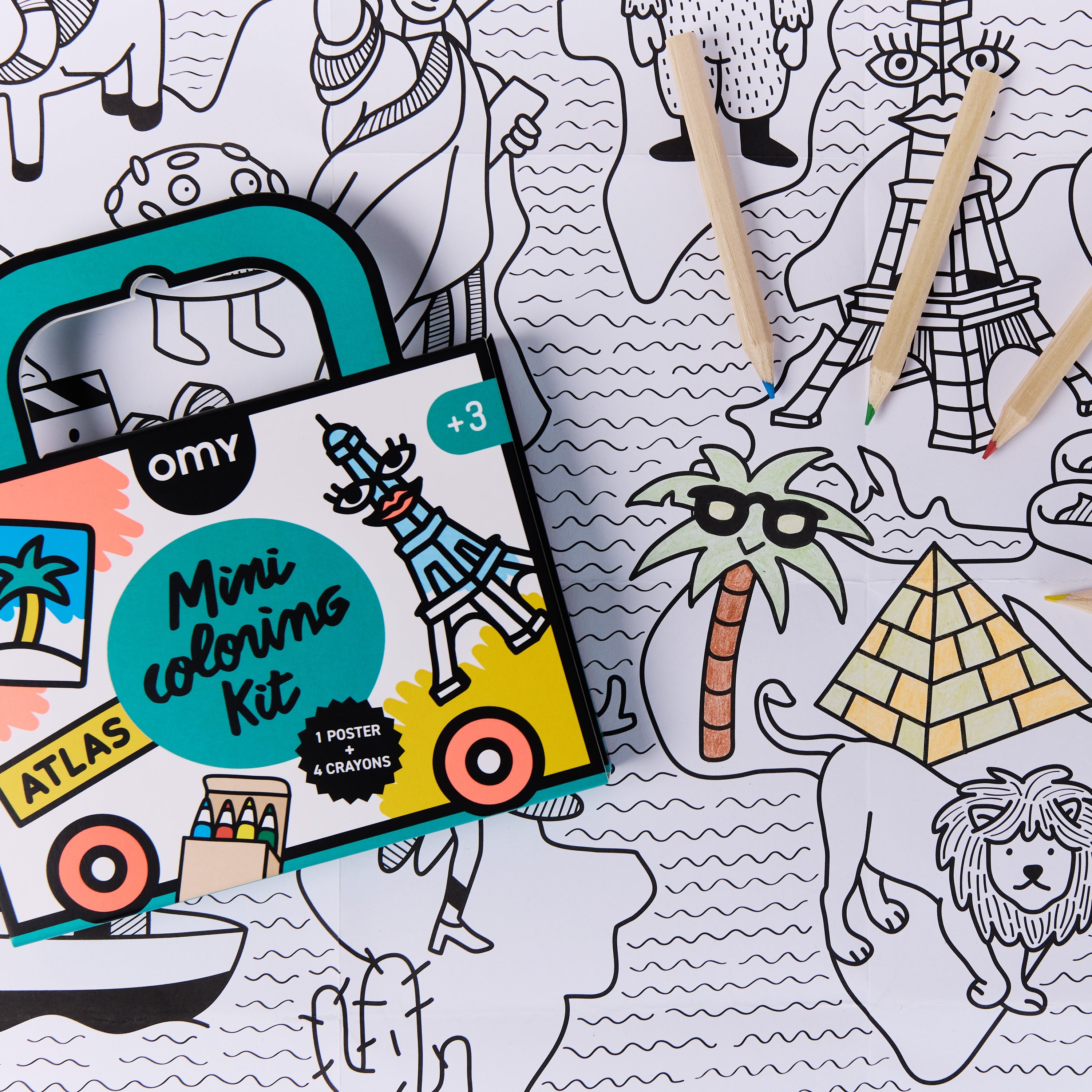 Gros plan du Mini Coloring Kit Atlas d’OMY France sur le poster carte du monde à colorier avec crayons colorés mettant en évidence pyramides et palmier — kit de coloriage nomade de voyage pour enfants, activité créative en déplacement en Europe.