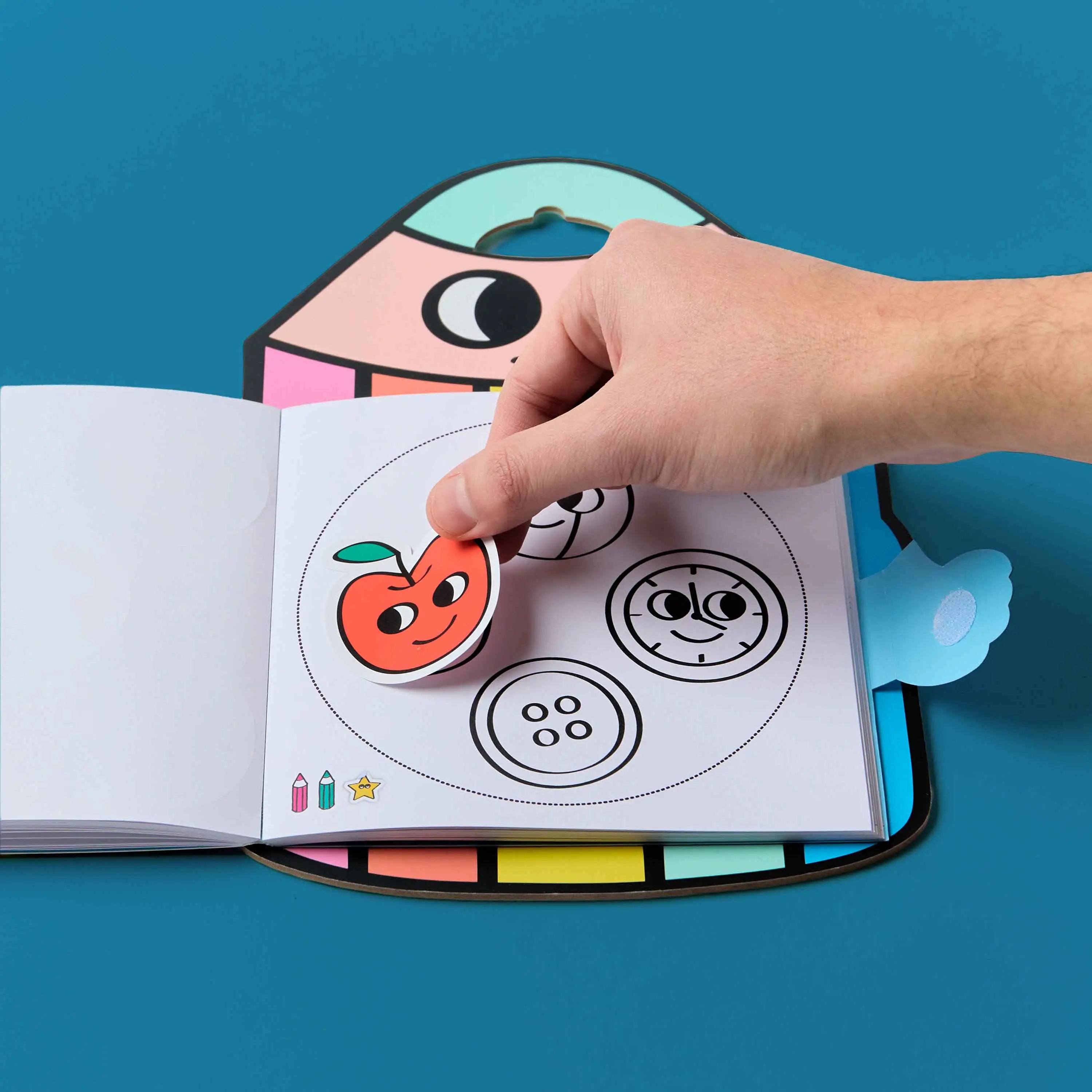 Main utilisant des stickers dans Montessori Stickers Book - Geometric Shapes, livre de coloriage éducatif OMY