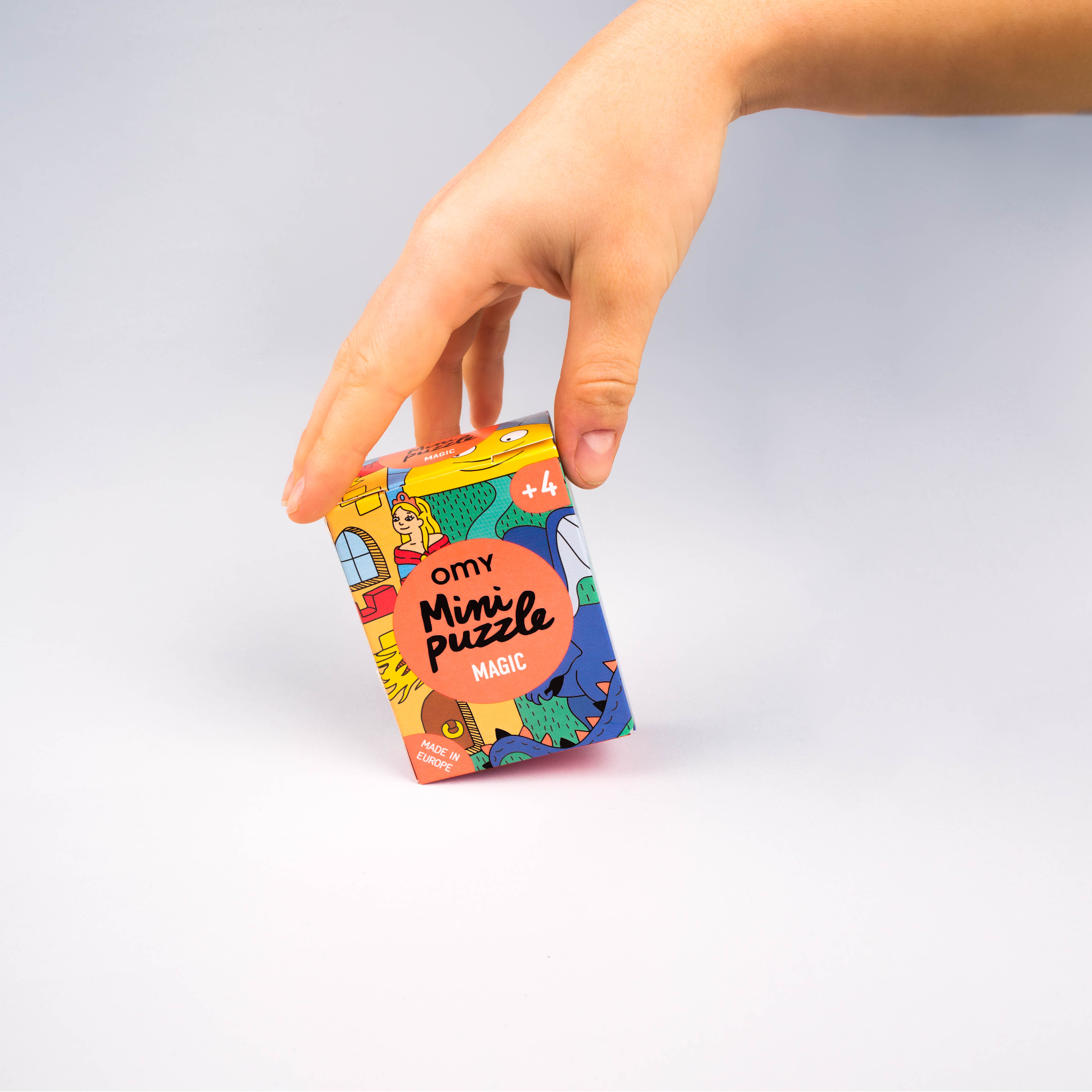 Mano che tiene la scatola del Mini Puzzle Magic OMY, illustrata con castello, principessa e drago, dai 4 anni, fabbricato in Europa