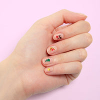 Hand with nude nails decorated with OMY NYC nail stickers: I love NY, Statue of Liberty and smiley, on a pink background.