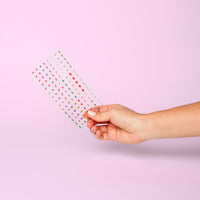 Sheet of OMY NYC nail stickers held in hand: small colorful New York motifs, on a pink background.