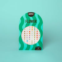 Groene golvende verpakking van de 120 Flower OMY Body Art nagelstickers, met een vel kleine bloemen, op een turquoise achtergrond.