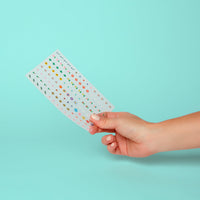 Stickervel met Flower OMY-nagelstickers in de hand: kleine bloemen en kleurrijk loof, op een turquoise achtergrond.