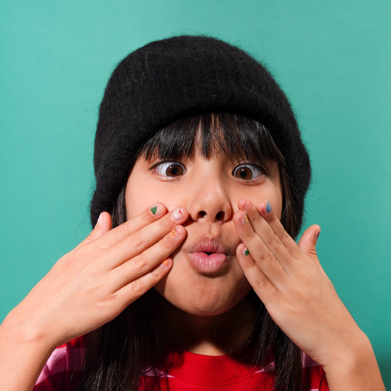 Petite fille exprimant sa joie en montrant ses ongles décorés avec les nail stickers OMY "HO HO HO!" pour les fêtes de fin d’année.